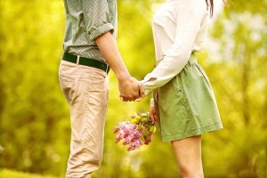 couple in love in park smiling holding a bouquet of lilac flowers in their hands. Valentine's Day